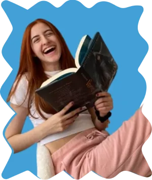 A woman laughing joyfully while holding an open book in her hands.